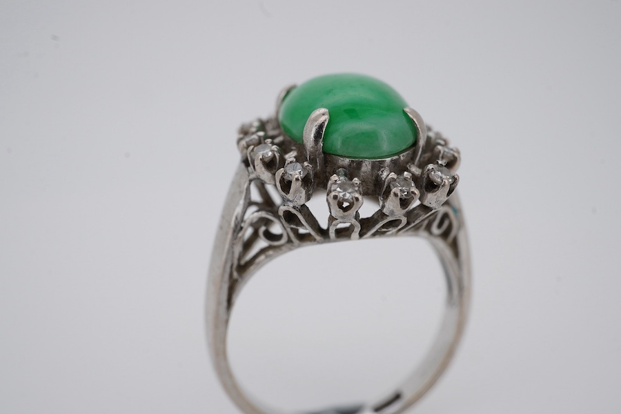 A white metal and cabochon jade set ring, with round cut diamond set border, size N, gross weight 5.4 grams. Condition - fair to good